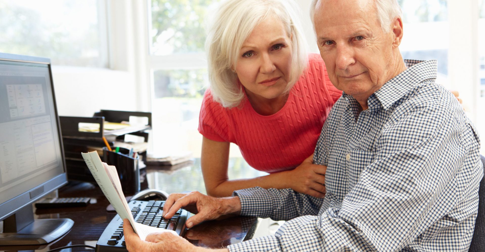 Senior man and woman using computer at home